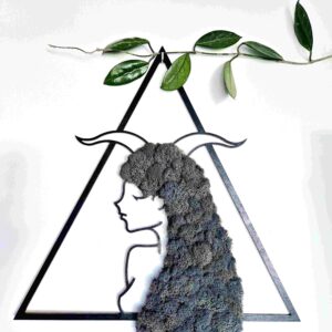 Obraz dekoracyjny z naturalnego szarego chrobotka reniferowego przedstawiający kobiecą postać znaku zodiaku Koziorożec z rogami na głowie, w czarnej trójkątnej ramie o wymiarach 45 cm; rękodzieło w stylu boho i japandi, nasycone energią Reiki, symbolizujące siłę, wytrwałość i duchową harmonię.