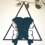 Zdjęcie przedstawia dekorację ścienną interpretującą znak zodiaku ryby. Dwa profile kobiece zwrócone w przeciwną stronę, które połączone są włosami wykonanymi z chrobotka reniferowego w kolorze morskim. Ich włosy układają się w rybie ogony.