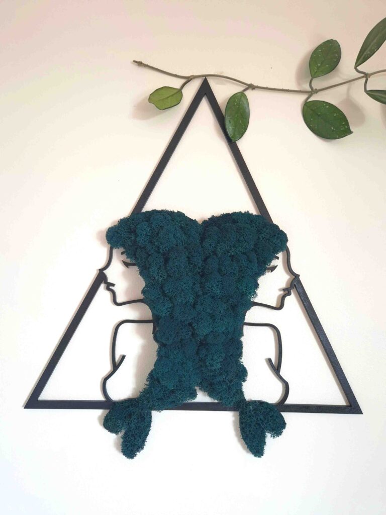 Zdjęcie przedstawia dekorację ścienną interpretującą znak zodiaku ryby. Dwa profile kobiece zwrócone w przeciwną stronę, które połączone są włosami wykonanymi z chrobotka reniferowego w kolorze morskim. Ich włosy układają się w rybie ogony.