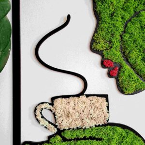 Zdjęcie przedstawia dekorację ścienną. Kobieta z jasnozielonego chrobotka z ustami w kolorze czerwonego chrobotka reniferowego. Kobieta trzyma na dłoniach filiżankę w jasnobeżowym kolorze chrobotka.