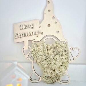 Skrzat ze sklejki z brodą z chrobotka reniferowego w kolorze beżowym/naturalnym. Skrzat trzyma drewnianą tabliczkę z napisem „Merry Christmas”.